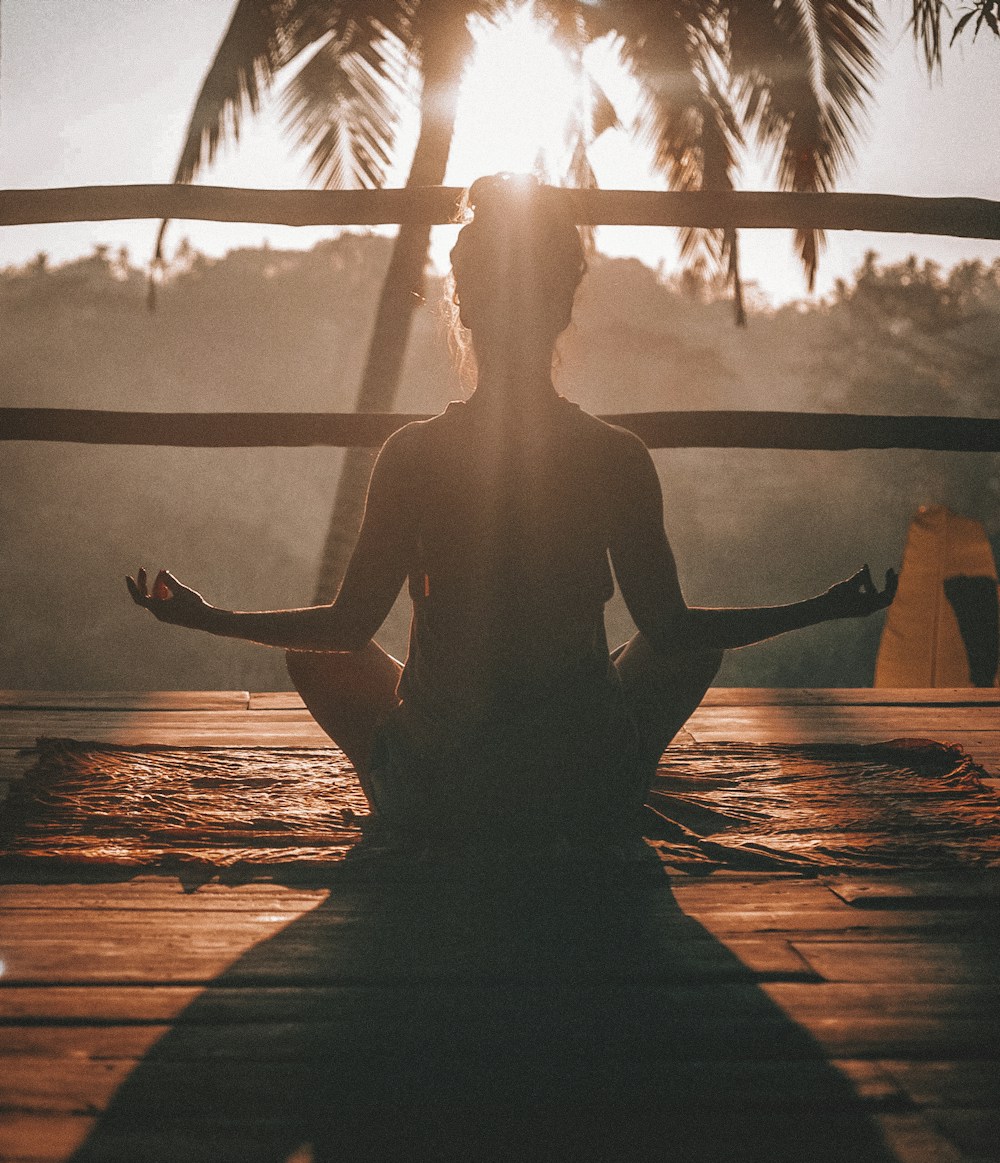 Person practising yoga beside a window at sunrise